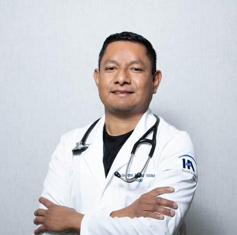 Professional portrait of a male doctor wearing a white lab coat and stethoscope against a white background