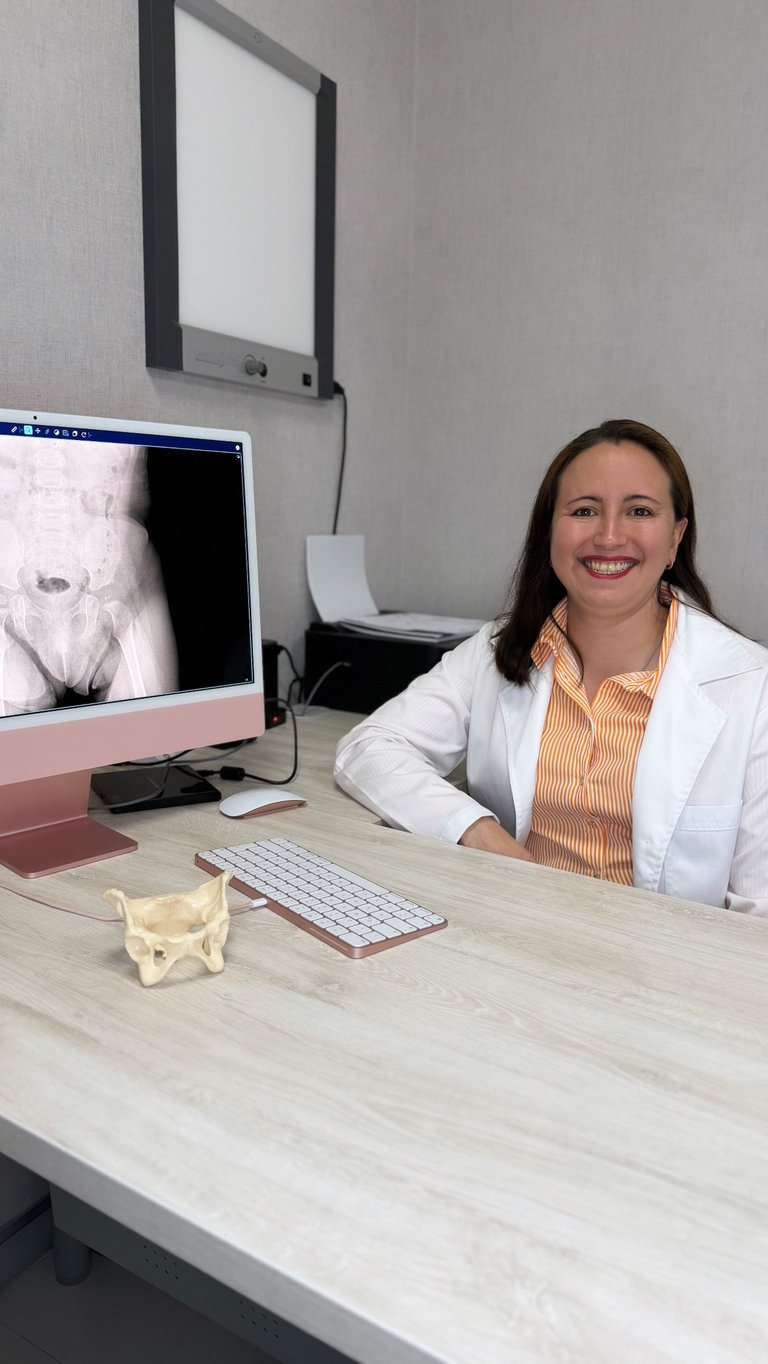 Professional woman sitting at desk in office with computer monitor, keyboard, and medical imaging displayed on screen